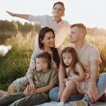 A family of five enjoying a serene picnic in a sunlit meadow during sunset.
